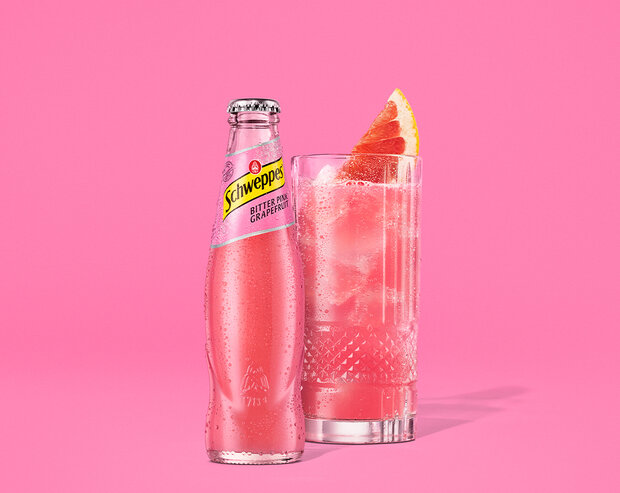 Schweppes Bitter Pink Grapefruit als 0,2 Liter Flasche vor pinkem Hintergrund