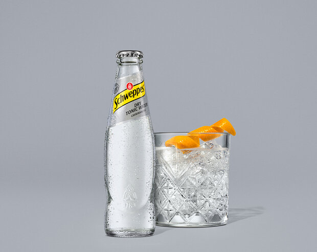 Schweppes Dry Tonic Water – gekühlte 0,2-l Glasflasche mit Kondensperlen auf grauem Hintergrund.