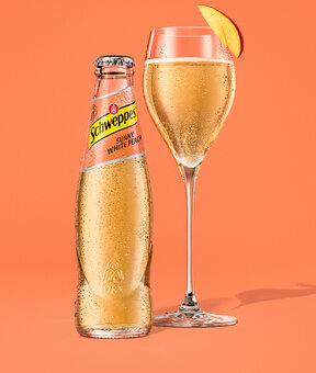 Schweppes White Peach – Glasflasche neben 1,25-l Flasche, beide mit Kondensperlen.